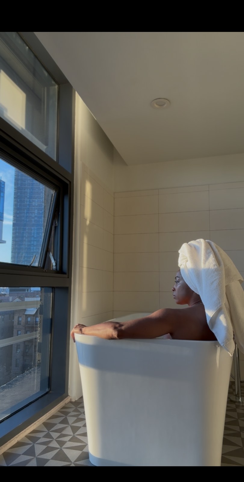 Resting in a deep bath, towel crown, golden hour through the window.
