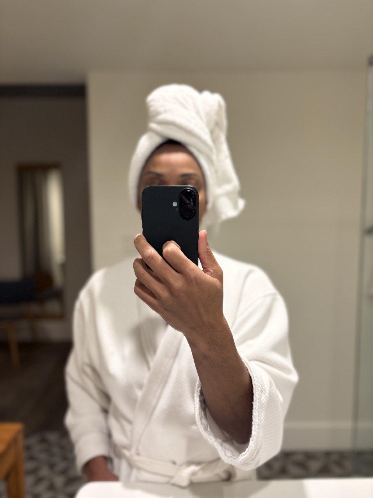 Mirror reflection in a white robe and towel crown.