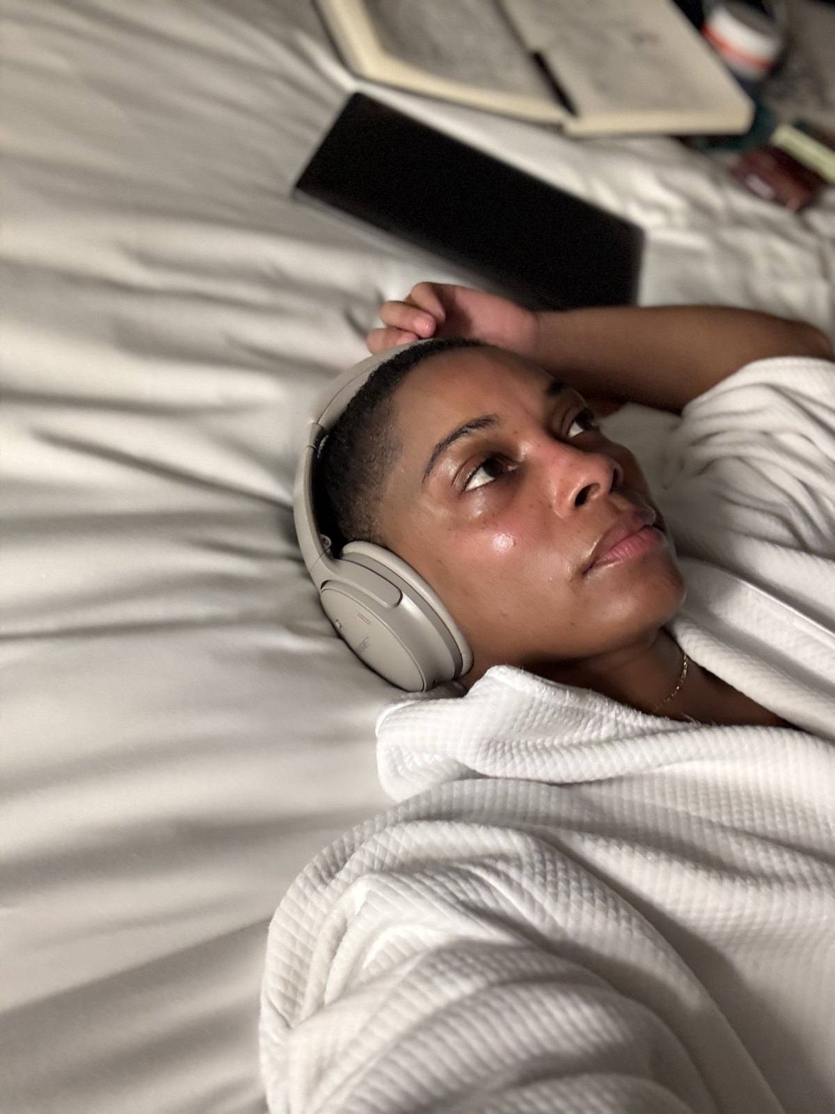 Lying back with headphones on, eyes up, completely at ease.