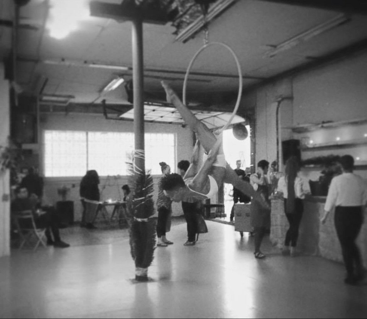 Suspended in the Lyra hoop mid-performance, black and white.